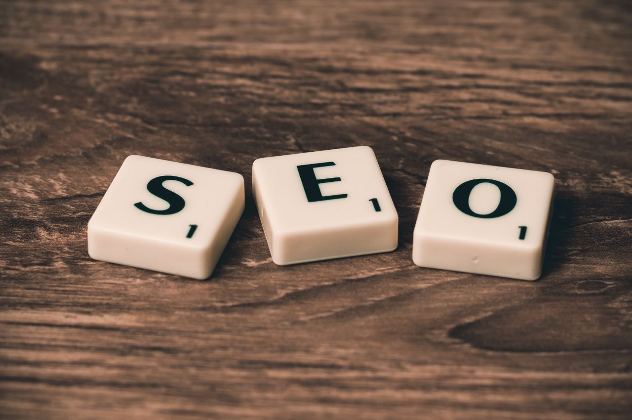 Lettered Scrabble tiles arranged to spell SEO on a wooden surface, perfect for digital marketing visuals.